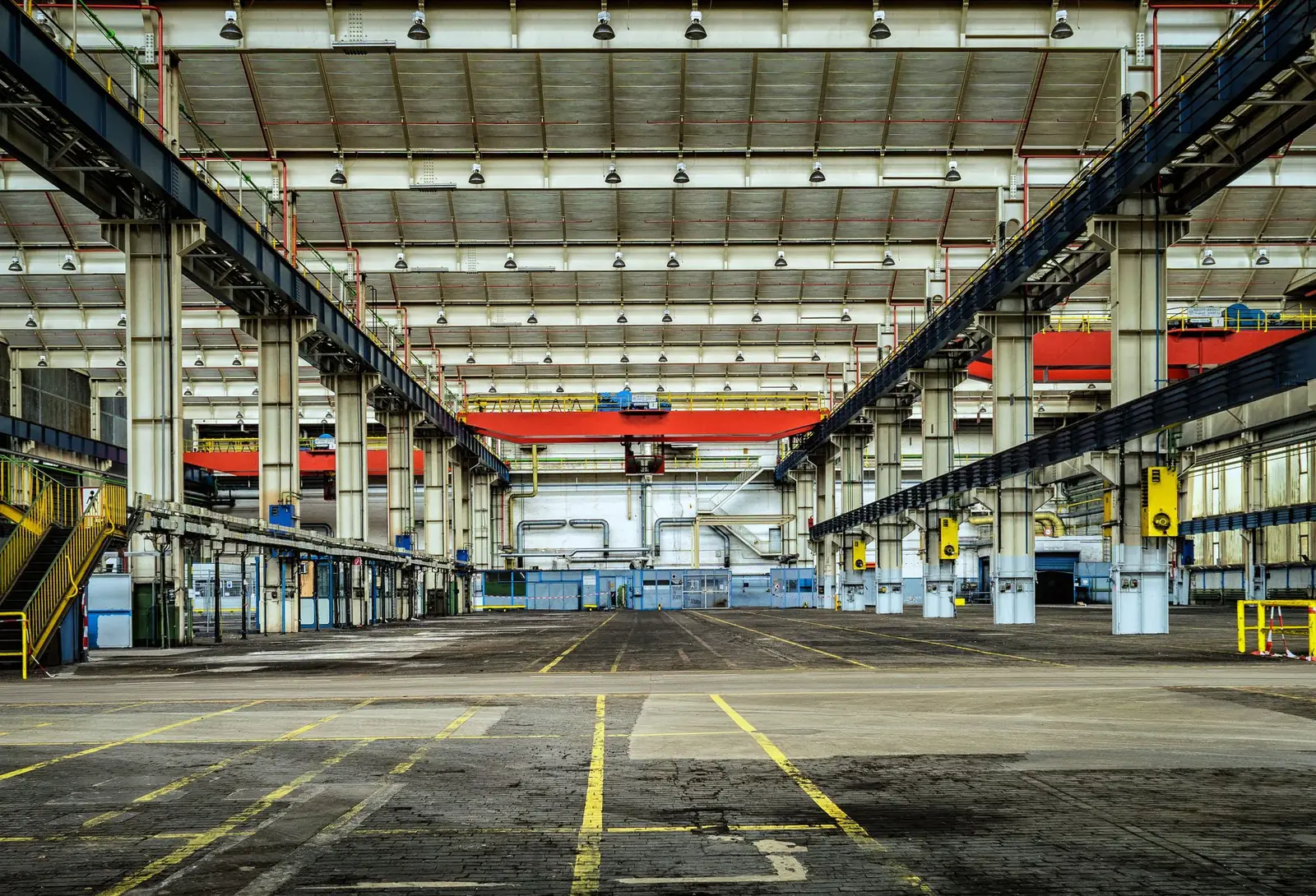 Leere Industriehalle mit Stahlträgern, Kranbahn und Bodenmarkierungen, Symbolbild